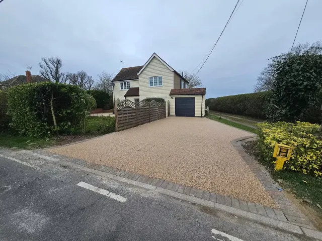 Gold gravel resin driveway with a block paved apron at a weatherboarded house