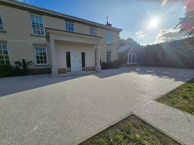 Pale silver resin driveway in front of a rendered house with a portico