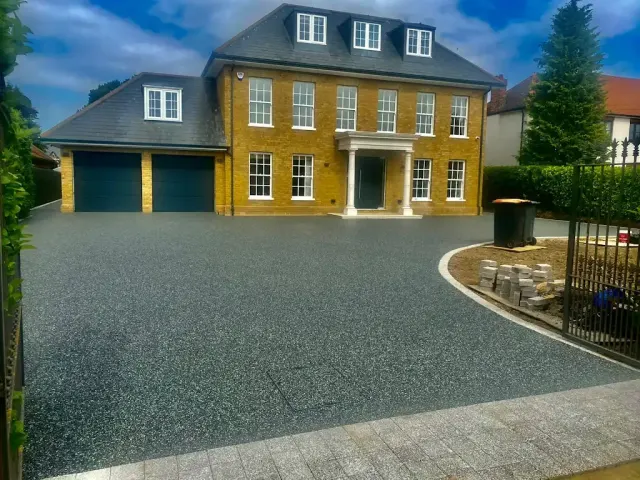 Blue-black resin driveway in front of a large house with a double garage