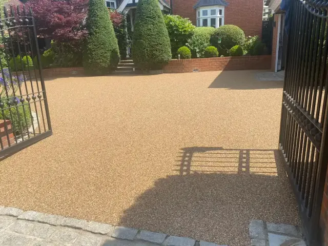 Amber resin driveway between iron gates with clipped topiary either side