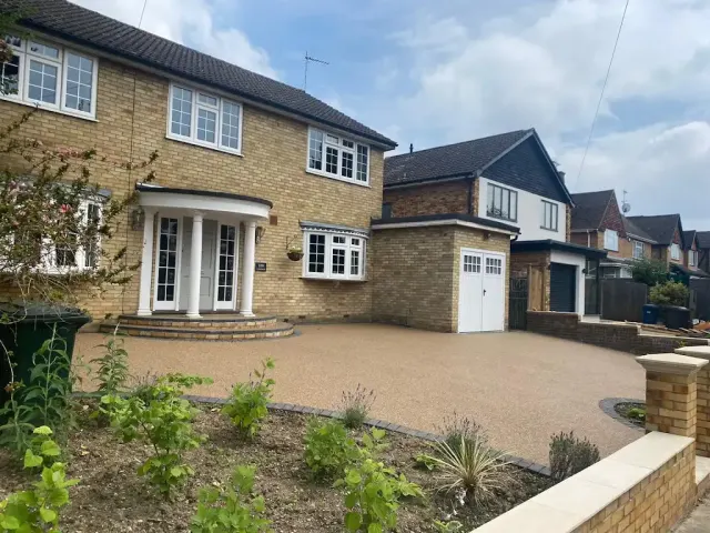 Gold resin driveway curving to a brick house with a pillared porch