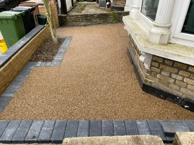 Gold resin side path with a charcoal block border beside a bay window