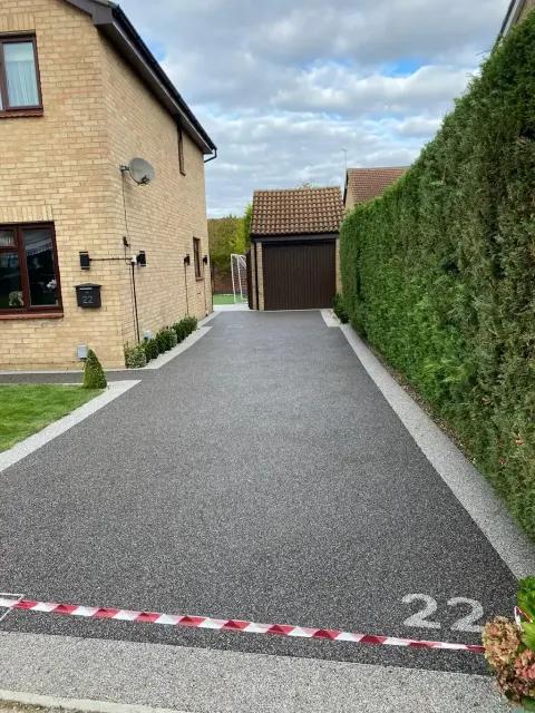 Charcoal resin driveway running down the side of a house to a garage