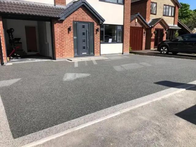 Charcoal resin driveway across a modern semi with an open garage