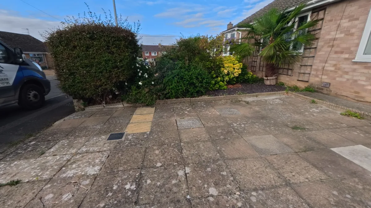 The driveway before the work: uneven concrete paving slabs, stained and cracked, with weeds growing through the joints.